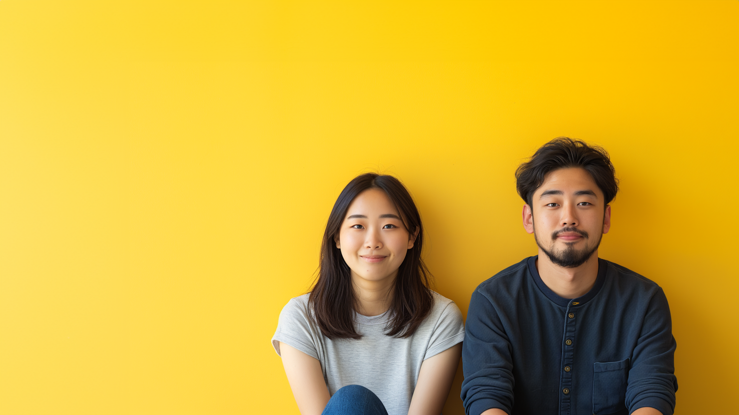Two friends sitting in front of a yellow wall